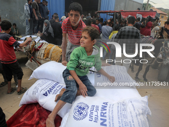 A Palestinian boy sits on top of sacks of flour at a United Nations Relief and Works Agency (UNRWA) aid distribution center amid the Israel-...