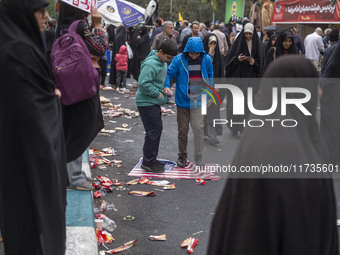 Two Iranian schoolboys stand on the U.S. flag during an anti-U.S. and anti-Israel rally marking the anniversary of the U.S. embassy occupati...