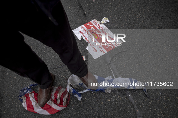 An Iranian protester stands on burnt U.S. and Israeli flags while participating in an anti-U.S. and anti-Israel rally marking the anniversar...