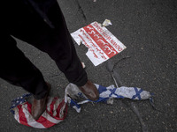 An Iranian protester stands on burnt U.S. and Israeli flags while participating in an anti-U.S. and anti-Israel rally marking the anniversar...