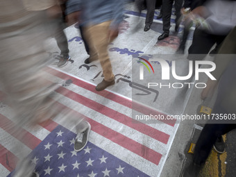 Iranian protesters walk on the U.S. flag and a banner featuring a portrait of the former U.S. President, Donald Trump, while participating i...