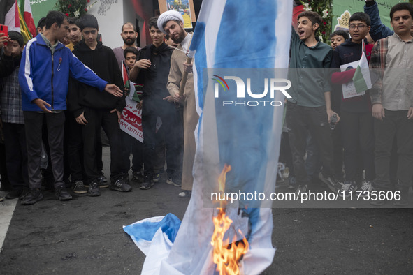 An Iranian cleric burns an Israeli flag out of the former U.S. embassy during an anti-U.S. and anti-Israel rally marking the anniversary of...