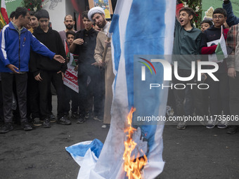 An Iranian cleric burns an Israeli flag out of the former U.S. embassy during an anti-U.S. and anti-Israel rally marking the anniversary of...