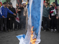 An Iranian cleric burns an Israeli flag out of the former U.S. embassy during an anti-U.S. and anti-Israel rally marking the anniversary of...