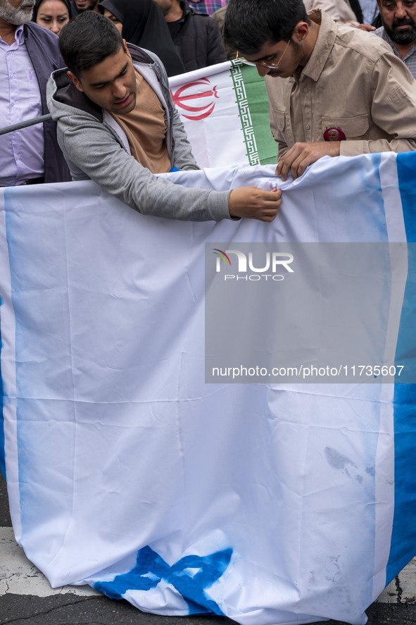 Two Iranian students prepare the U.S. flag to set on fire outside the former U.S. embassy during an anti-U.S. and anti-Israel rally marking...