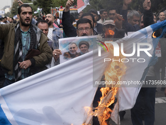 An Iranian man holds a poster featuring portraits of Lebanon's Hezbollah late leader, Hassan Nasrallah, and an IRGC's Quds Force commander,...