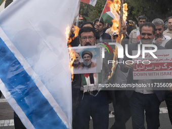 An Iranian man holds a poster featuring portraits of Lebanon's Hezbollah late leader, Hassan Nasrallah, and an IRGC's Quds Force commander,...