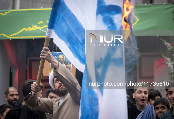 An Iranian cleric burns an Israeli flag out of the former U.S. embassy during an anti-U.S. and anti-Israel rally marking the anniversary of...