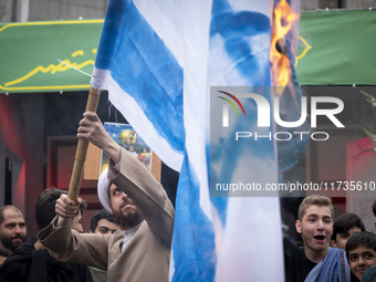 An Iranian cleric burns an Israeli flag out of the former U.S. embassy during an anti-U.S. and anti-Israel rally marking the anniversary of...