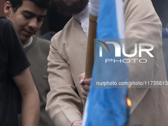 An Iranian cleric smiles while burning an Israeli flag out of the former U.S. embassy during an anti-U.S. and anti-Israel rally marking the...