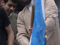 An Iranian cleric smiles while burning an Israeli flag out of the former U.S. embassy during an anti-U.S. and anti-Israel rally marking the...