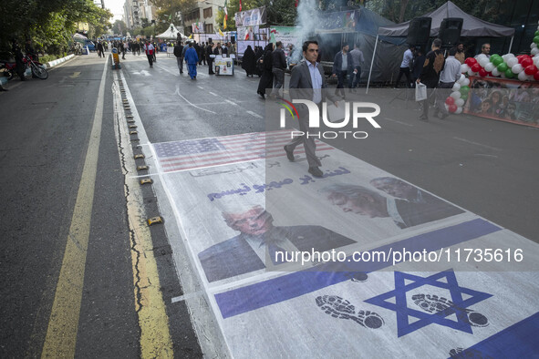 An Iranian man participates in an anti-U.S. and anti-Israel rally marking the anniversary of the U.S. embassy occupation, walking on the U.S...