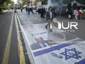 An Iranian man participates in an anti-U.S. and anti-Israel rally marking the anniversary of the U.S. embassy occupation, walking on the U.S...