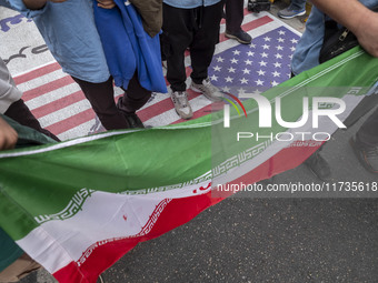 Iranian students hold an Iranian flag and stand on the U.S. flag while participating in an anti-U.S. and anti-Israel rally marking the anniv...