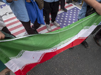 Iranian students hold an Iranian flag and stand on the U.S. flag while participating in an anti-U.S. and anti-Israel rally marking the anniv...