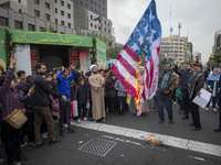 An Iranian cleric burns the U.S. flag outside the former U.S. embassy during an anti-U.S. and anti-Israel rally marking the anniversary of t...