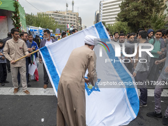 An Iranian cleric prepares an Israeli flag to set on fire outside the former U.S. embassy during an anti-U.S. and anti-Israel rally marking...