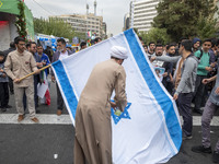 An Iranian cleric prepares an Israeli flag to set on fire outside the former U.S. embassy during an anti-U.S. and anti-Israel rally marking...