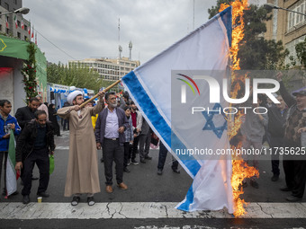 An Iranian cleric burns an Israeli flag out of the former U.S. embassy during an anti-U.S. and anti-Israel rally marking the anniversary of...