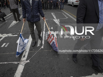 An Iranian man carries the U.S. and Israel flags while participating in an anti-U.S. and anti-Israel rally marking the anniversary of the U....