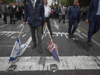 An Iranian man carries the U.S. and Israel flags while participating in an anti-U.S. and anti-Israel rally marking the anniversary of the U....