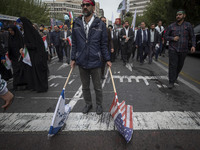 An Iranian man carries the U.S. and Israel flags while participating in an anti-U.S. and anti-Israel rally marking the anniversary of the U....