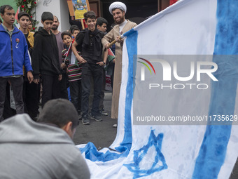 An Iranian cleric prepares an Israeli flag to set on fire outside the former U.S. embassy during an anti-U.S. and anti-Israel rally marking...