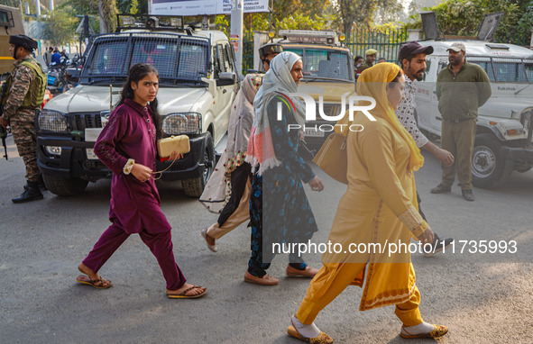 People walk past as security personnel stand near the site of a grenade blast at a marketplace in Srinagar, Jammu and Kashmir, on November 3...