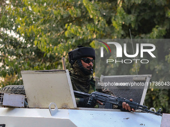 An Indian security personnel remains alert atop an armored vehicle near the site of a grenade blast at a marketplace in Srinagar, Jammu and...