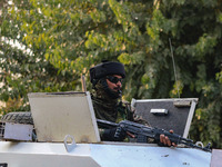 An Indian security personnel remains alert atop an armored vehicle near the site of a grenade blast at a marketplace in Srinagar, Jammu and...