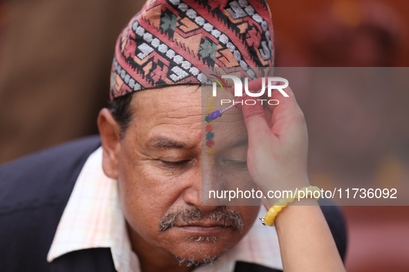 A Nepali Hindu receives a multi-colored tika on the forehead, marking the day of Bhaitika, the concluding day of Tihar, the five-day festiva...