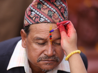 A Nepali Hindu receives a multi-colored tika on the forehead, marking the day of Bhaitika, the concluding day of Tihar, the five-day festiva...