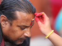 A Nepali Hindu receives a multi-colored tika on the forehead, marking the day of Bhaitika, the concluding day of Tihar, the five-day festiva...