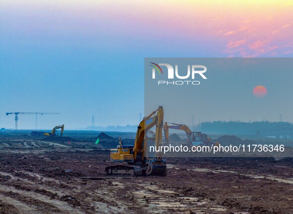 Workers operate large equipment at the construction site of the second phase of the Huaihe River Inlet Waterway project in Qingjiangpu distr...