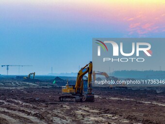 Workers operate large equipment at the construction site of the second phase of the Huaihe River Inlet Waterway project in Qingjiangpu distr...