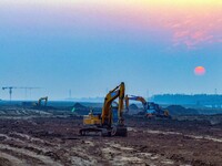 Workers operate large equipment at the construction site of the second phase of the Huaihe River Inlet Waterway project in Qingjiangpu distr...