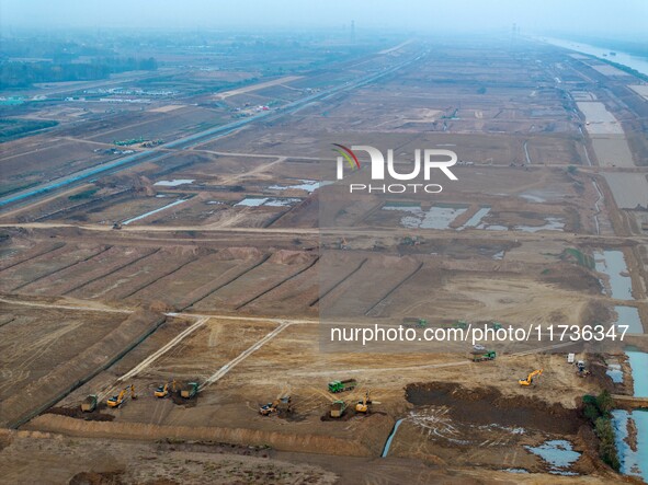 Workers operate large equipment at the construction site of the second phase of the Huaihe River Inlet Waterway project in Qingjiangpu distr...