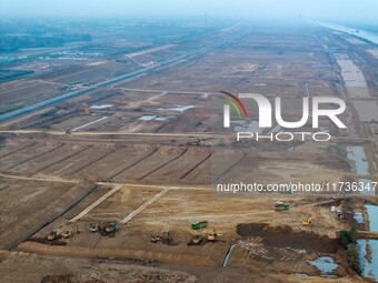 Workers operate large equipment at the construction site of the second phase of the Huaihe River Inlet Waterway project in Qingjiangpu distr...