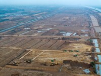 Workers operate large equipment at the construction site of the second phase of the Huaihe River Inlet Waterway project in Qingjiangpu distr...