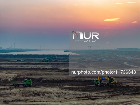 Workers operate large equipment at the construction site of the second phase of the Huaihe River Inlet Waterway project in Qingjiangpu distr...