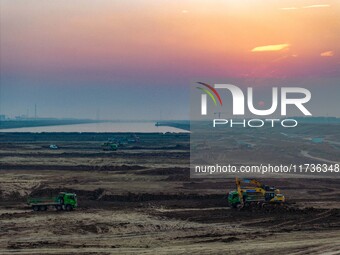 Workers operate large equipment at the construction site of the second phase of the Huaihe River Inlet Waterway project in Qingjiangpu distr...