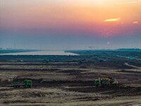 Workers operate large equipment at the construction site of the second phase of the Huaihe River Inlet Waterway project in Qingjiangpu distr...