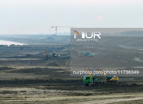 Workers operate large equipment at the construction site of the second phase of the Huaihe River Inlet Waterway project in Qingjiangpu distr...