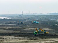 Workers operate large equipment at the construction site of the second phase of the Huaihe River Inlet Waterway project in Qingjiangpu distr...