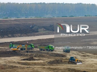 Workers operate large equipment at the construction site of the second phase of the Huaihe River Inlet Waterway project in Qingjiangpu distr...