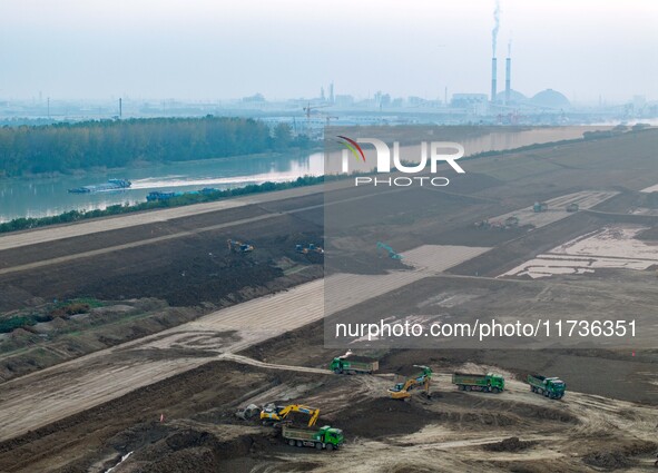 Workers operate large equipment at the construction site of the second phase of the Huaihe River Inlet Waterway project in Qingjiangpu distr...