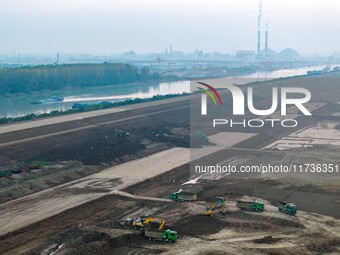 Workers operate large equipment at the construction site of the second phase of the Huaihe River Inlet Waterway project in Qingjiangpu distr...