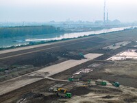 Workers operate large equipment at the construction site of the second phase of the Huaihe River Inlet Waterway project in Qingjiangpu distr...