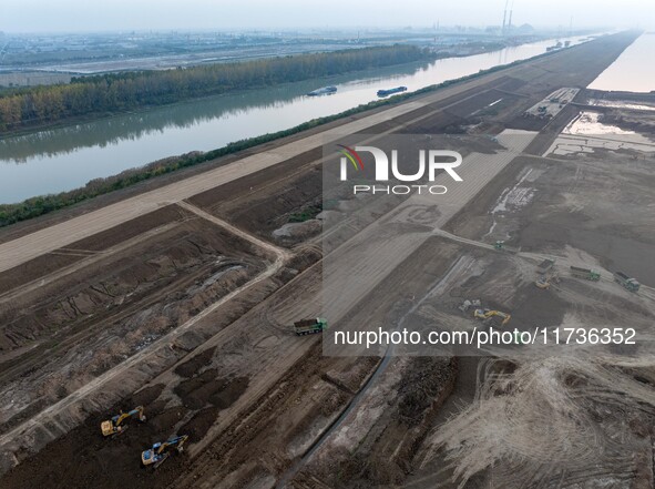 Workers operate large equipment at the construction site of the second phase of the Huaihe River Inlet Waterway project in Qingjiangpu distr...