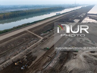 Workers operate large equipment at the construction site of the second phase of the Huaihe River Inlet Waterway project in Qingjiangpu distr...